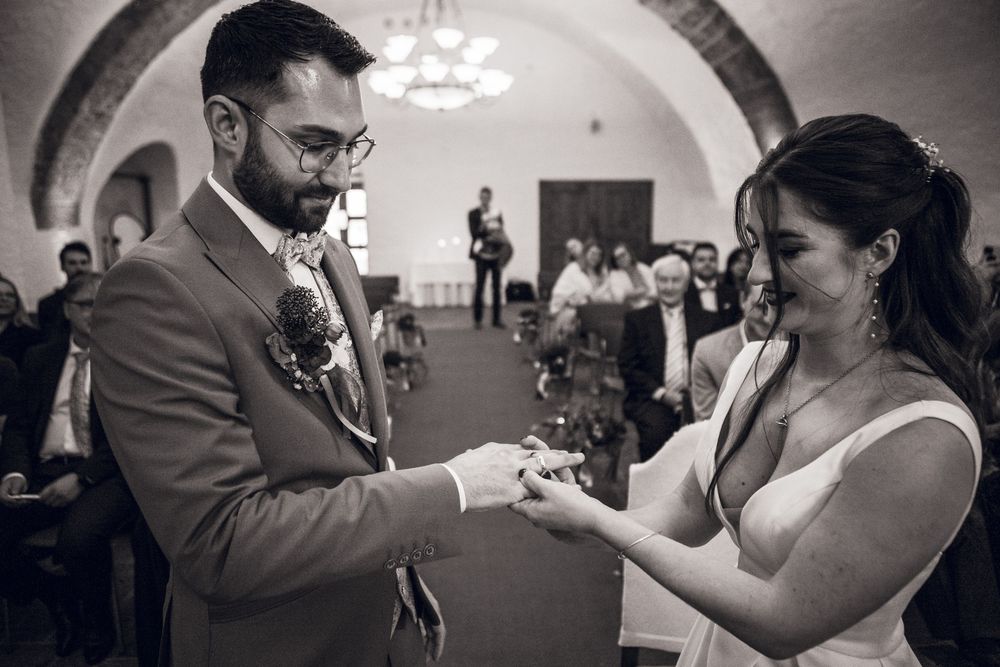 Bride and groom exchange rings during an intimate black and white wedding ceremony indoors.