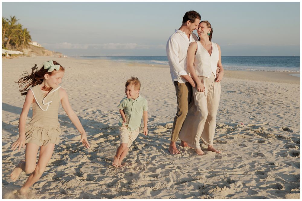 Punta Mita family photography session, family embracing and playing on a white sandy beach near the tropical shoreline.