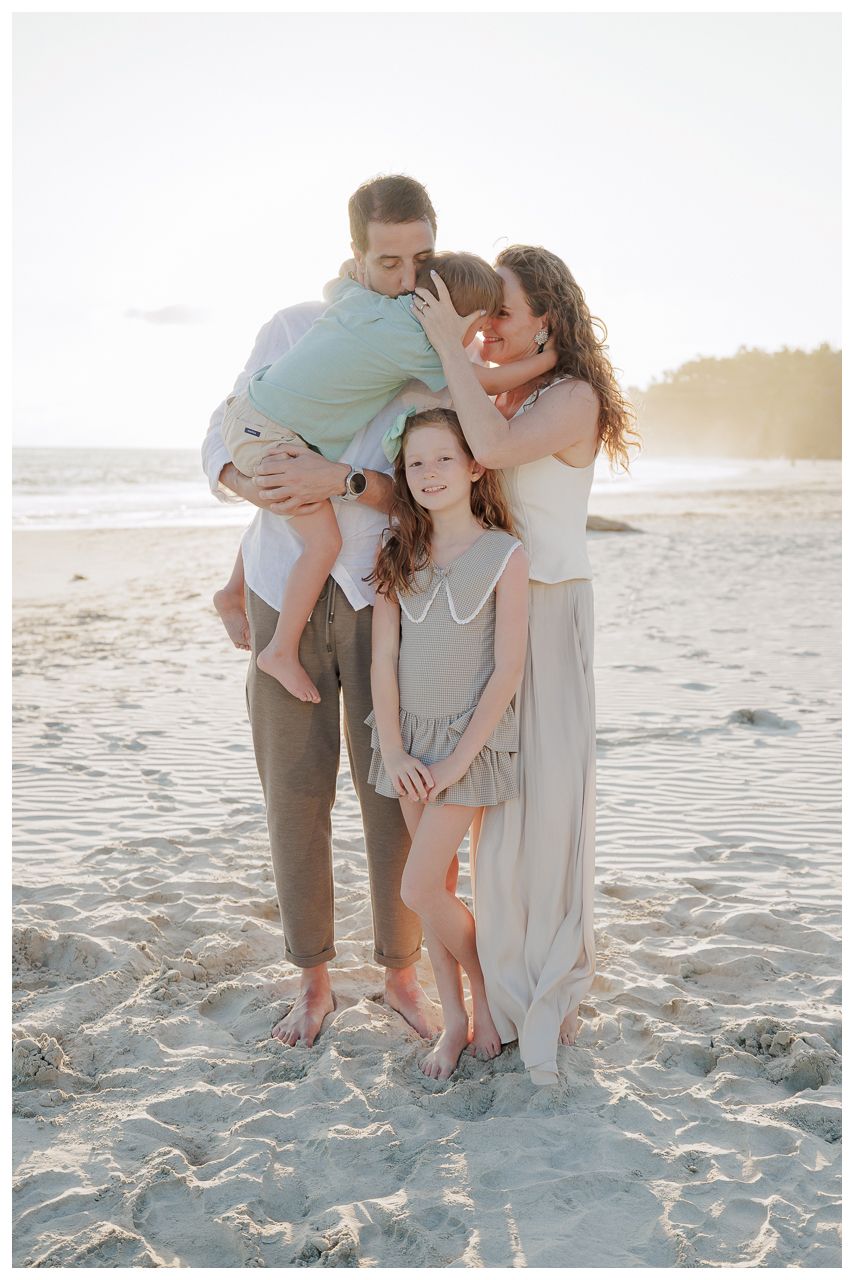Punta Mita family photography session, family of four sharing hugs on a sandy beach during golden hour.