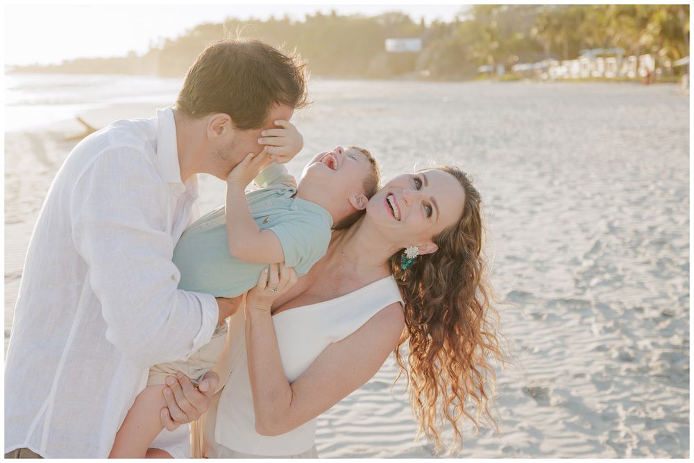 Punta Mita family photography, happy family laughing on a sunny beach while parents hold their baby during the day.