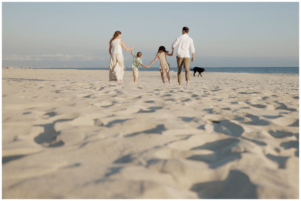 Punta Mita family photography, family walking with their dog along a wide sandy beach under a clear sky.