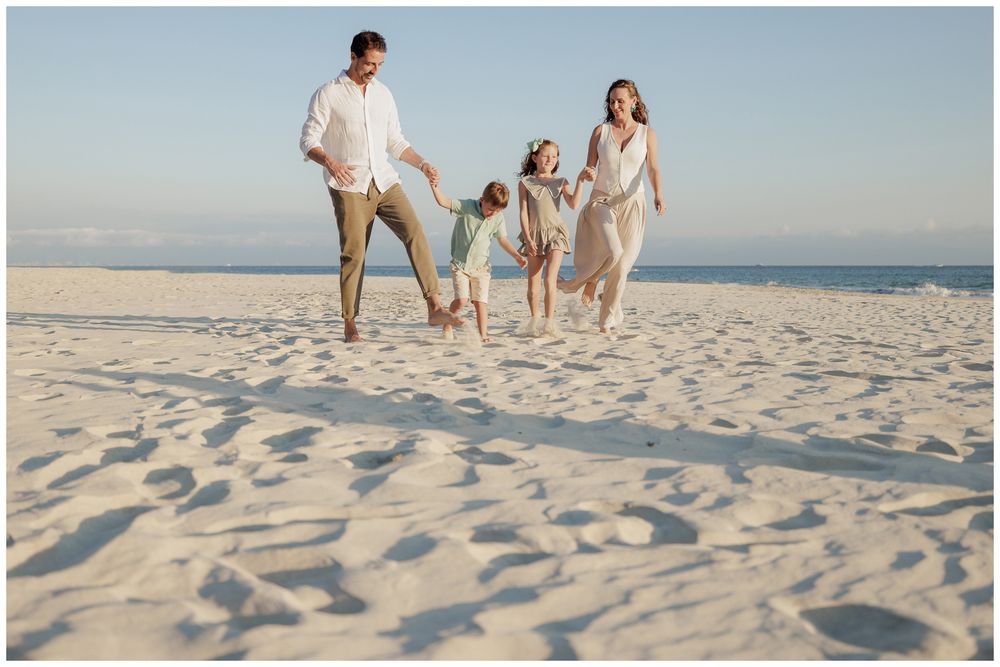 Punta Mita family photography session, family of four running and playing on a white sandy beach on a sunny day.