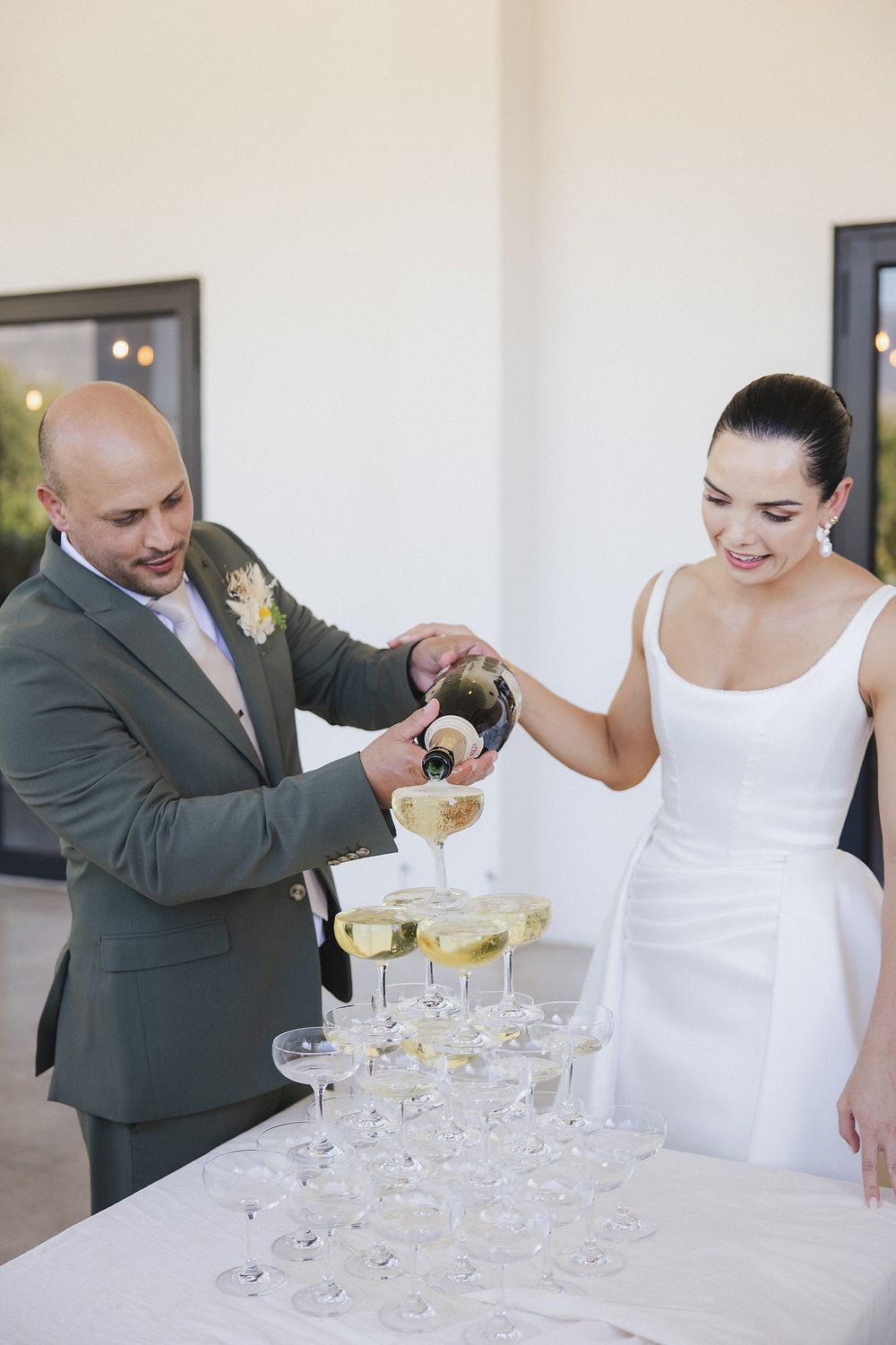 Bride and Groom pouring champagne into the tower at the canapes