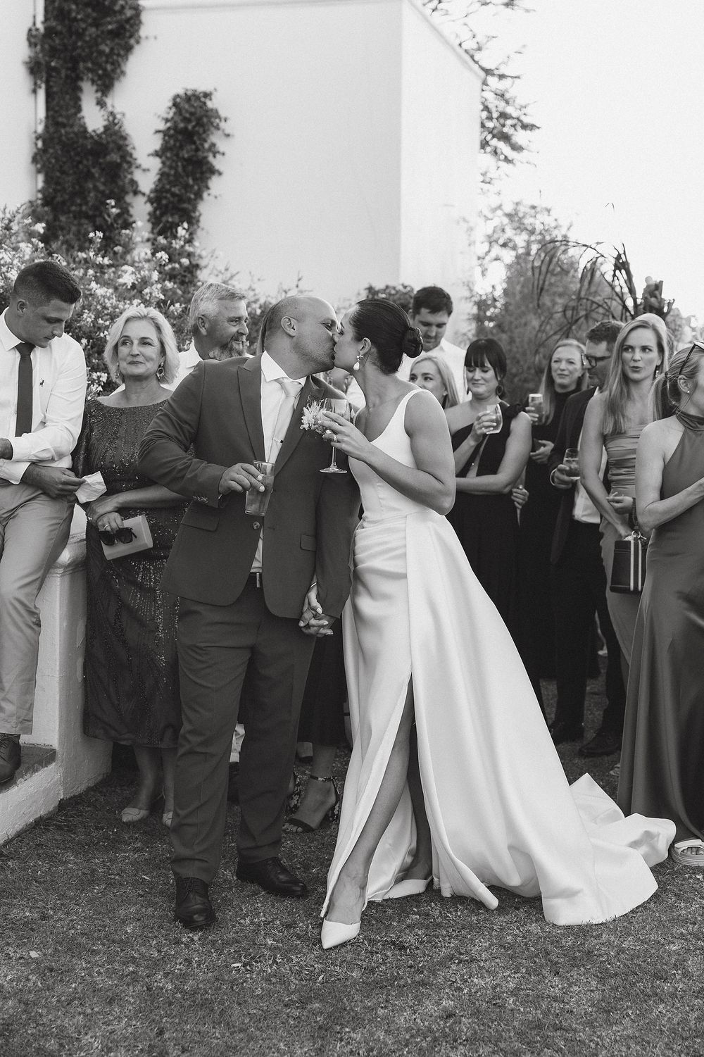 Bride and groom sharing a romantic kiss in front of friends and family