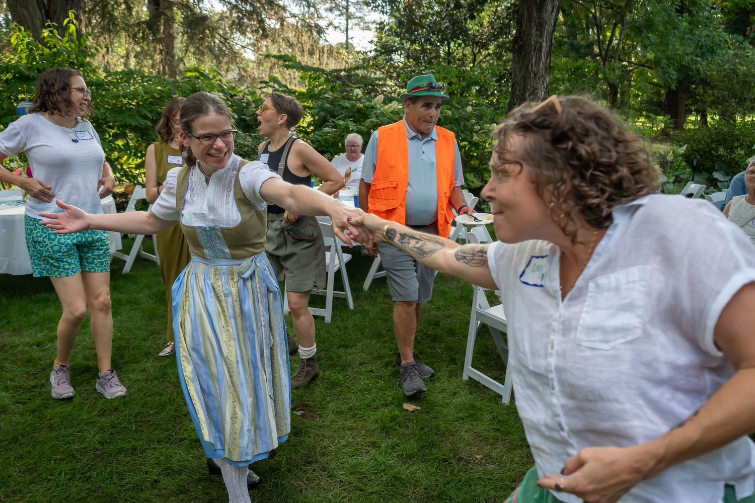 People enjoying an outdoor summer party engage in lively conversation and activities in a green garden setting.