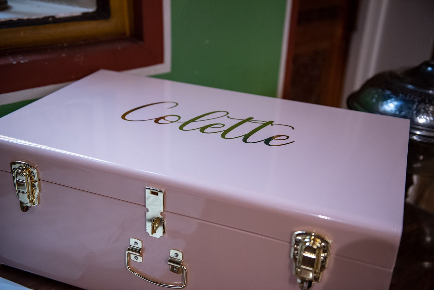 A pink personalized keepsake box with gold cursive lettering spelling Colette for a baptism gift.