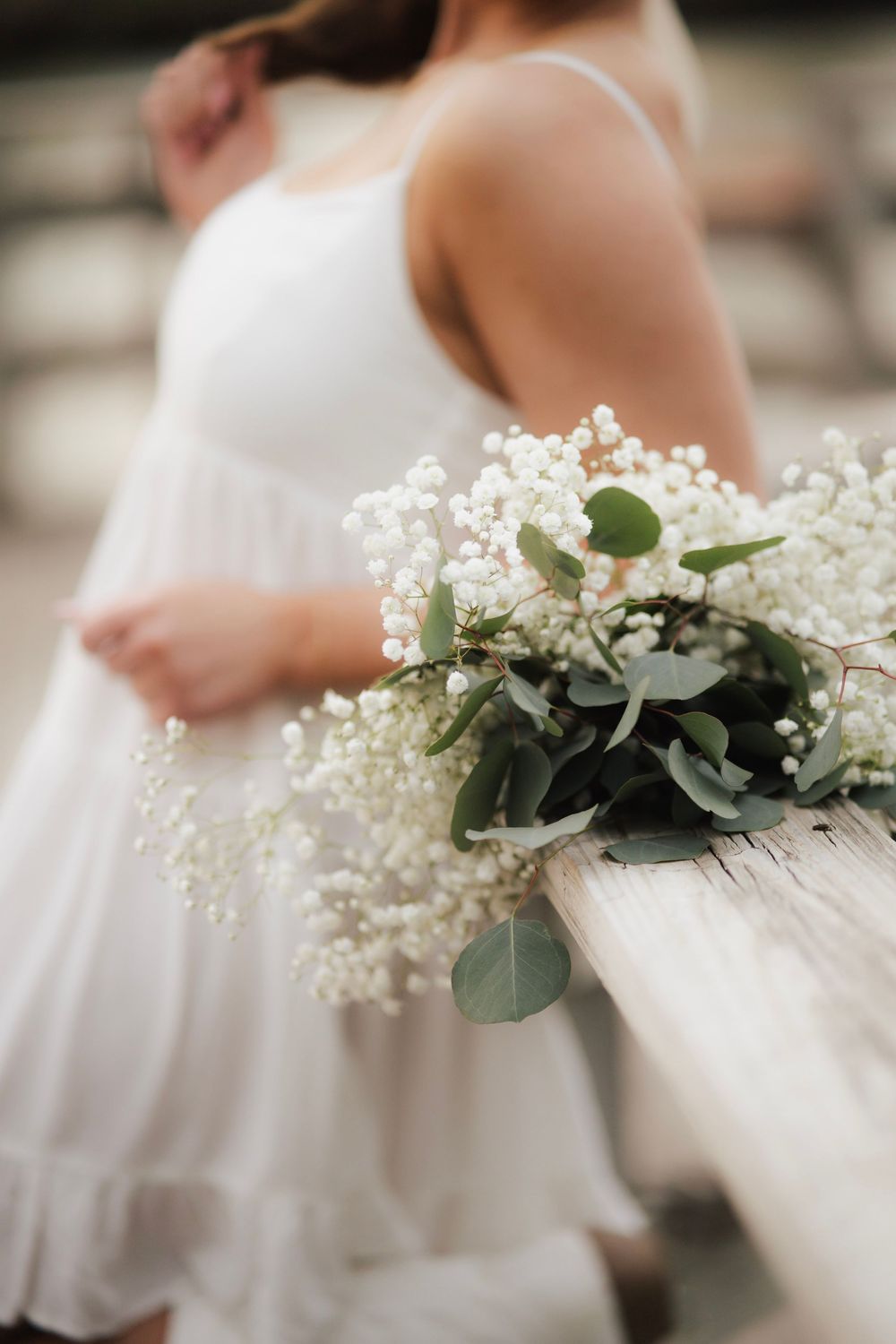 Close-up of white baby's breath and eucalyptus bouquet resting on wooden railing.