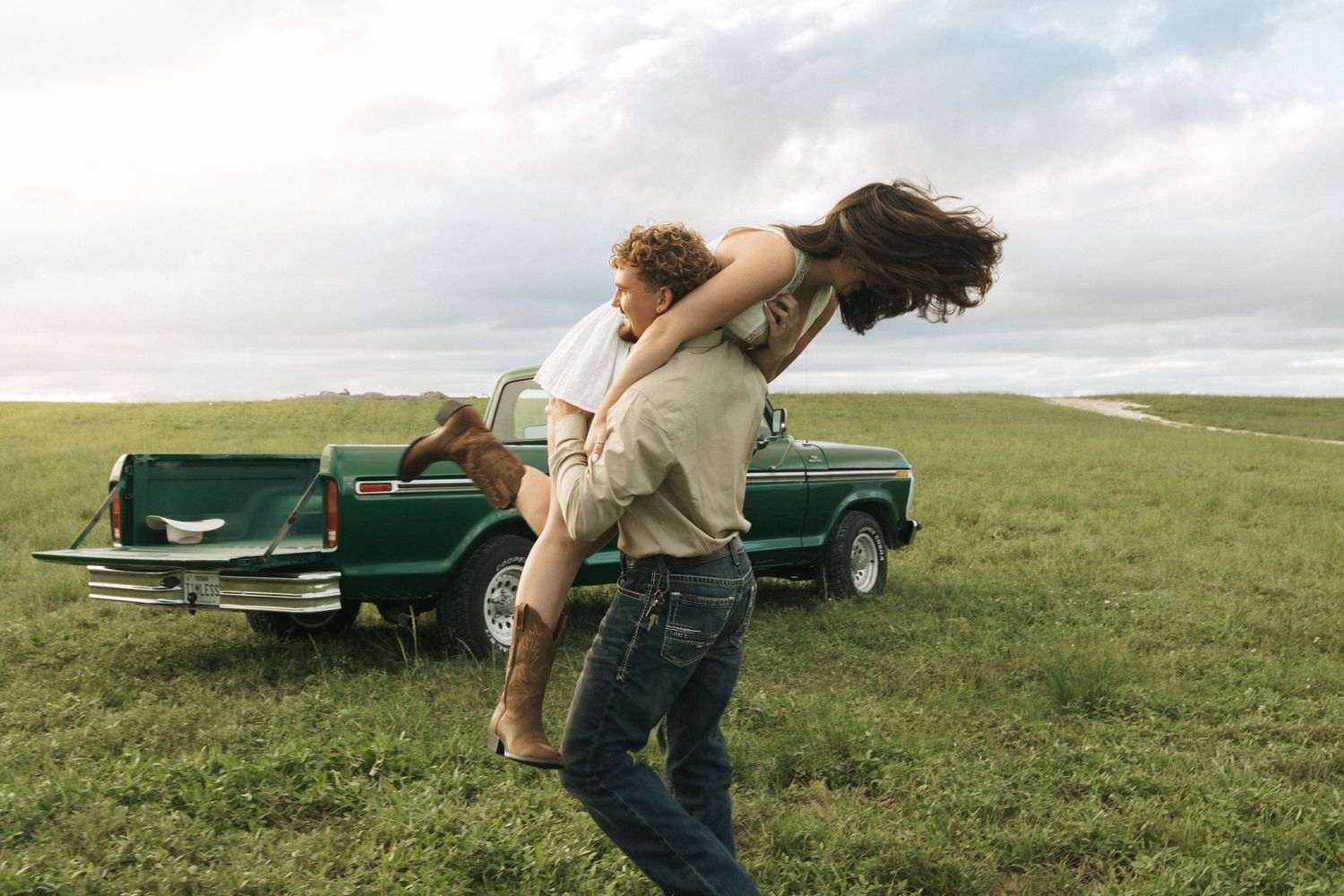 Couple being playful in field with vintage truck in florida