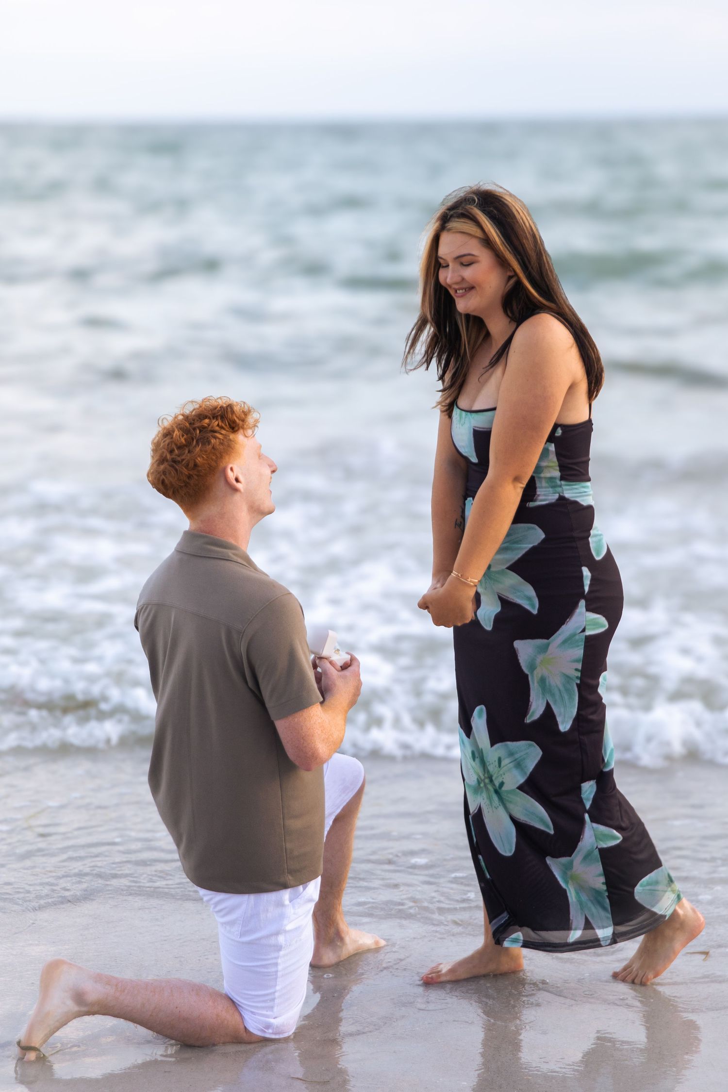 Couple sharing a romantic moment on a wooden bridge deck surrounded by lush oak trees in a park.
