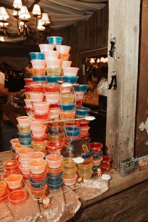 Colorful stacked jello shot cups arranged in a pyramid display at a rustic wedding reception venue.
