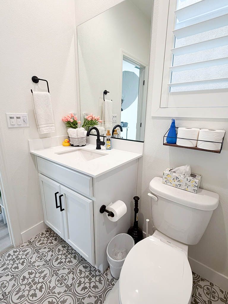 Menifee Photography Studio; Clean white bathroom with black fixtures, patterned tile floor, vanity, and window.