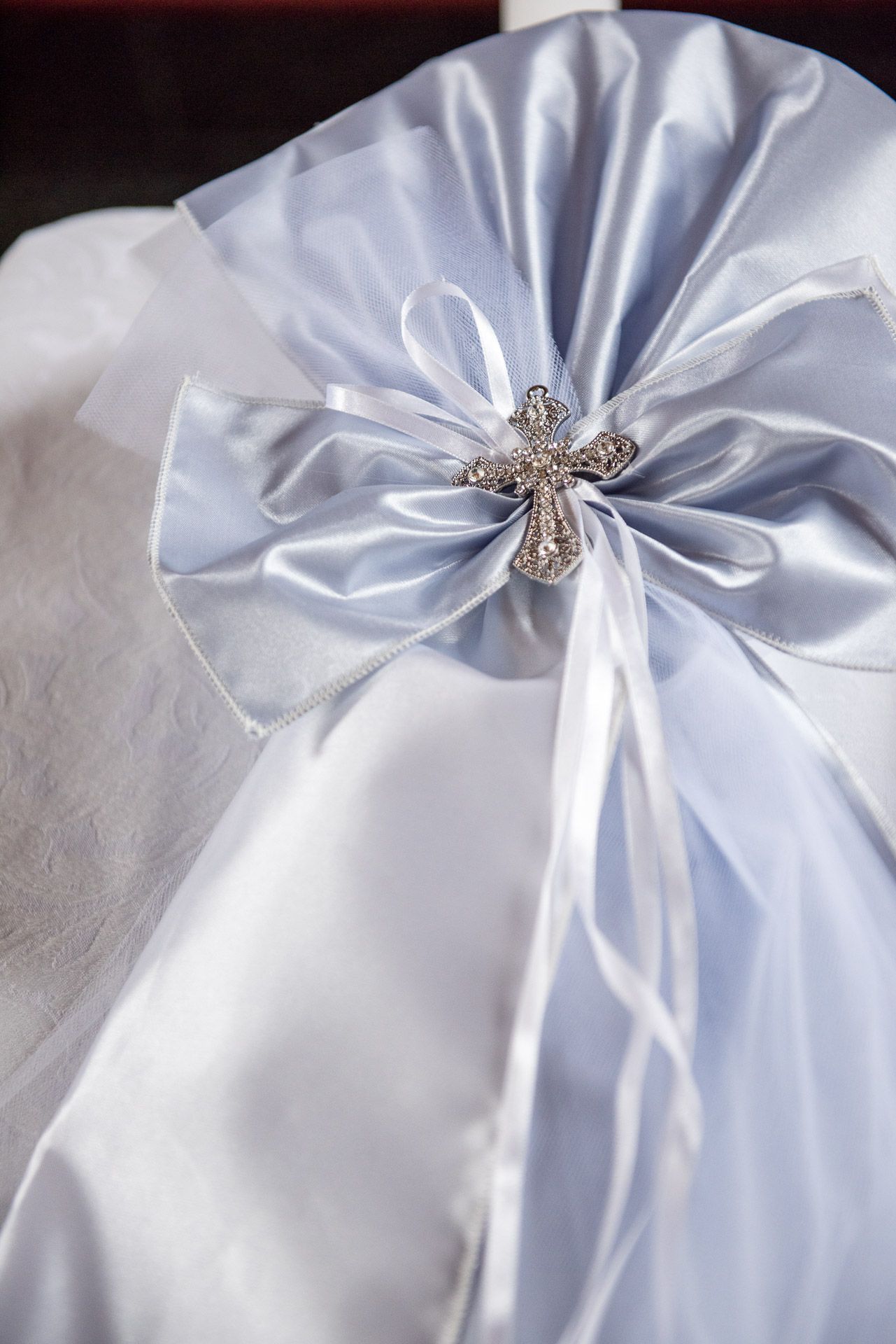 Elegant white and silver satin bow with crystal cross brooch on baptism candle decoration.