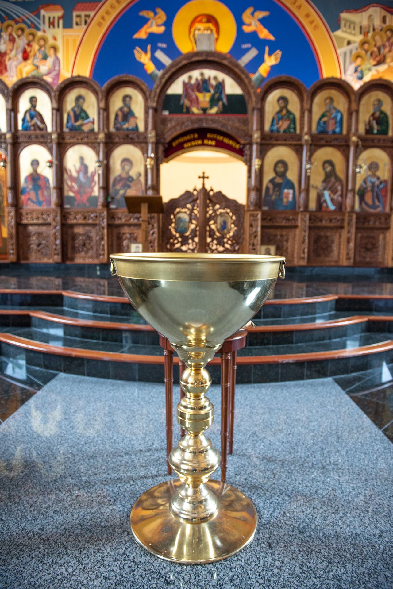 Golden chalice on marble altar in Orthodox church with colorful religious icon paintings.