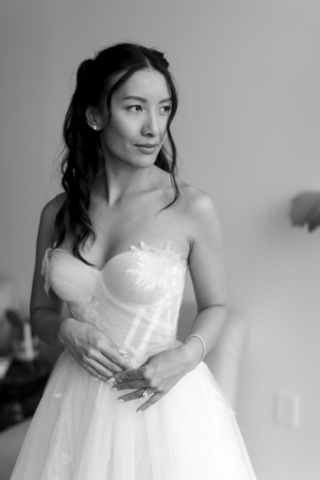 Person wearing a strapless white wedding gown in a classic black and white portrait.