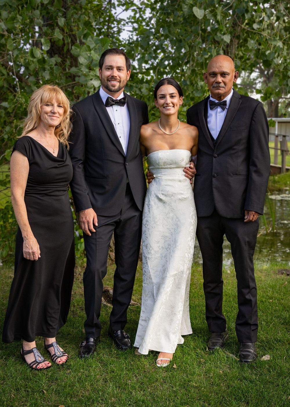 a bride and groom stand with parents.