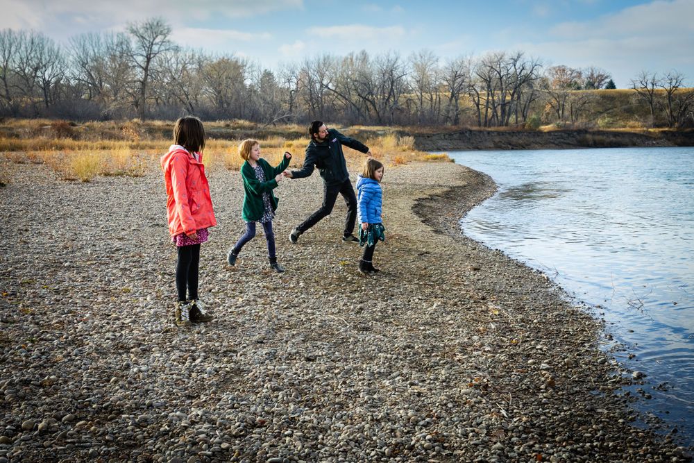 a family smiling together on a river bank.