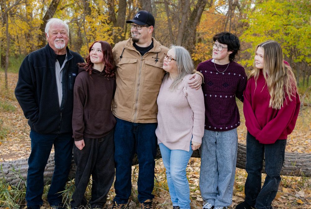 a family gathered together smiling, on an autumn day.