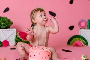 watermelon theme cake smash with toddler girl eating watermelon cake