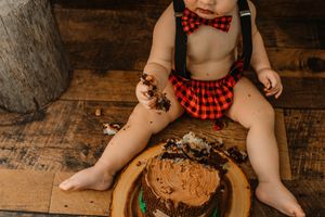 lumberjack theme cake smash with boy in plaid smashing chocolate cake