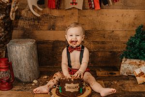 lumberjack theme cake smash with boy in plaid smashing chocolate cake