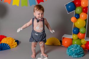 boy standing with cake all over hands and face