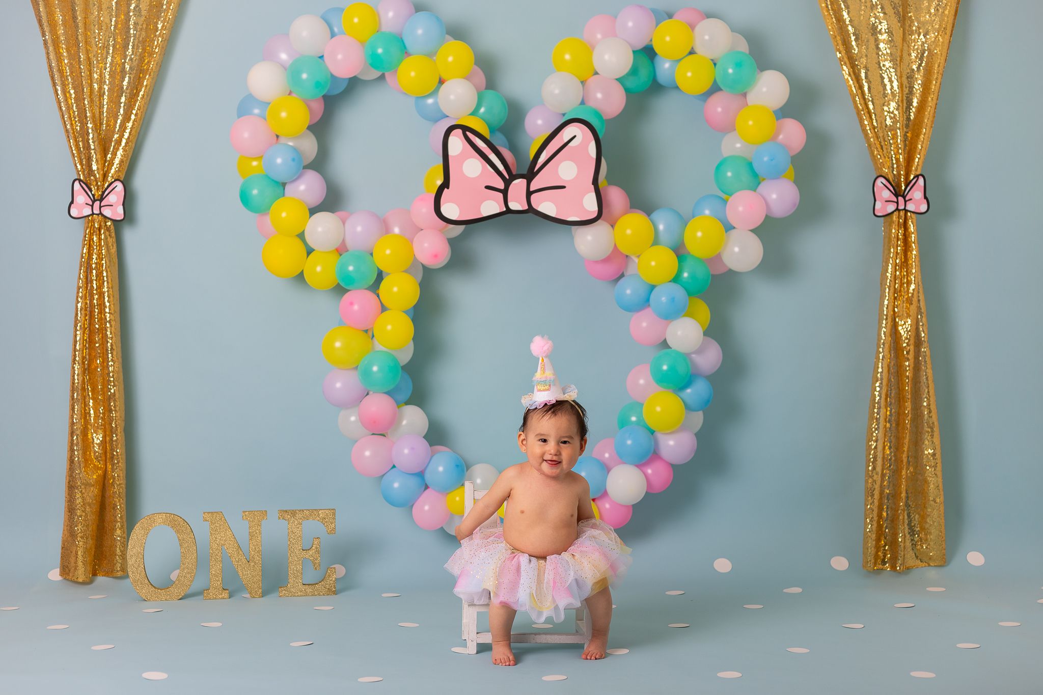 girl sitting on bench at mini mouse cake smash photoshoot