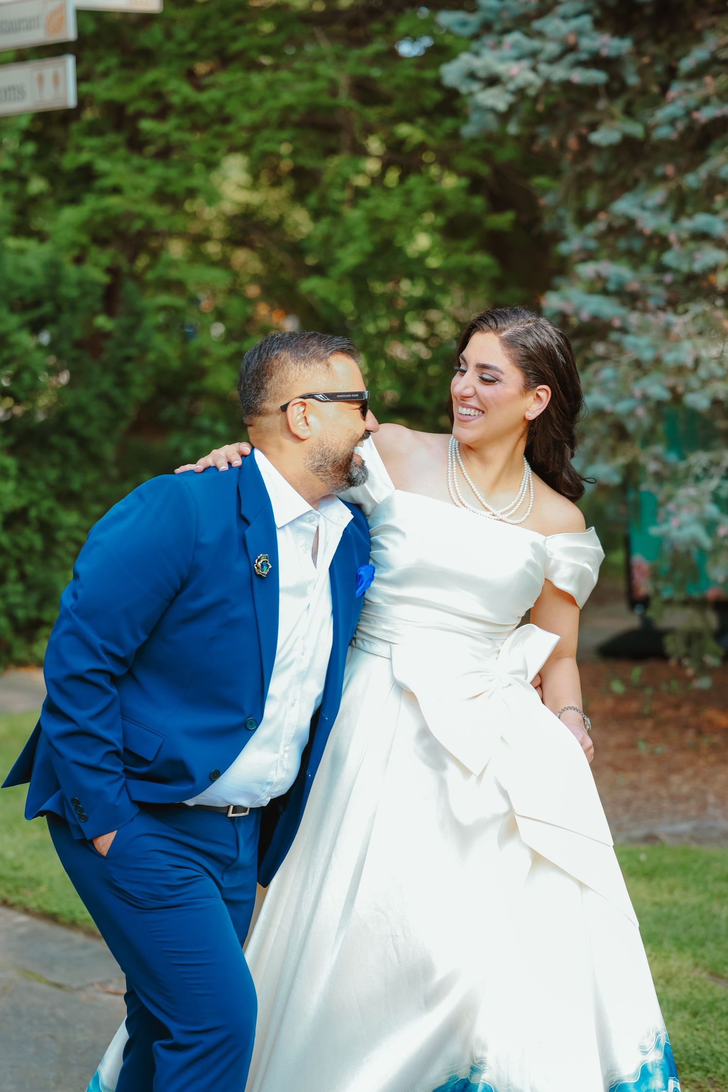 A couple shares a joyful moment outdoors wearing formal wedding attire.
