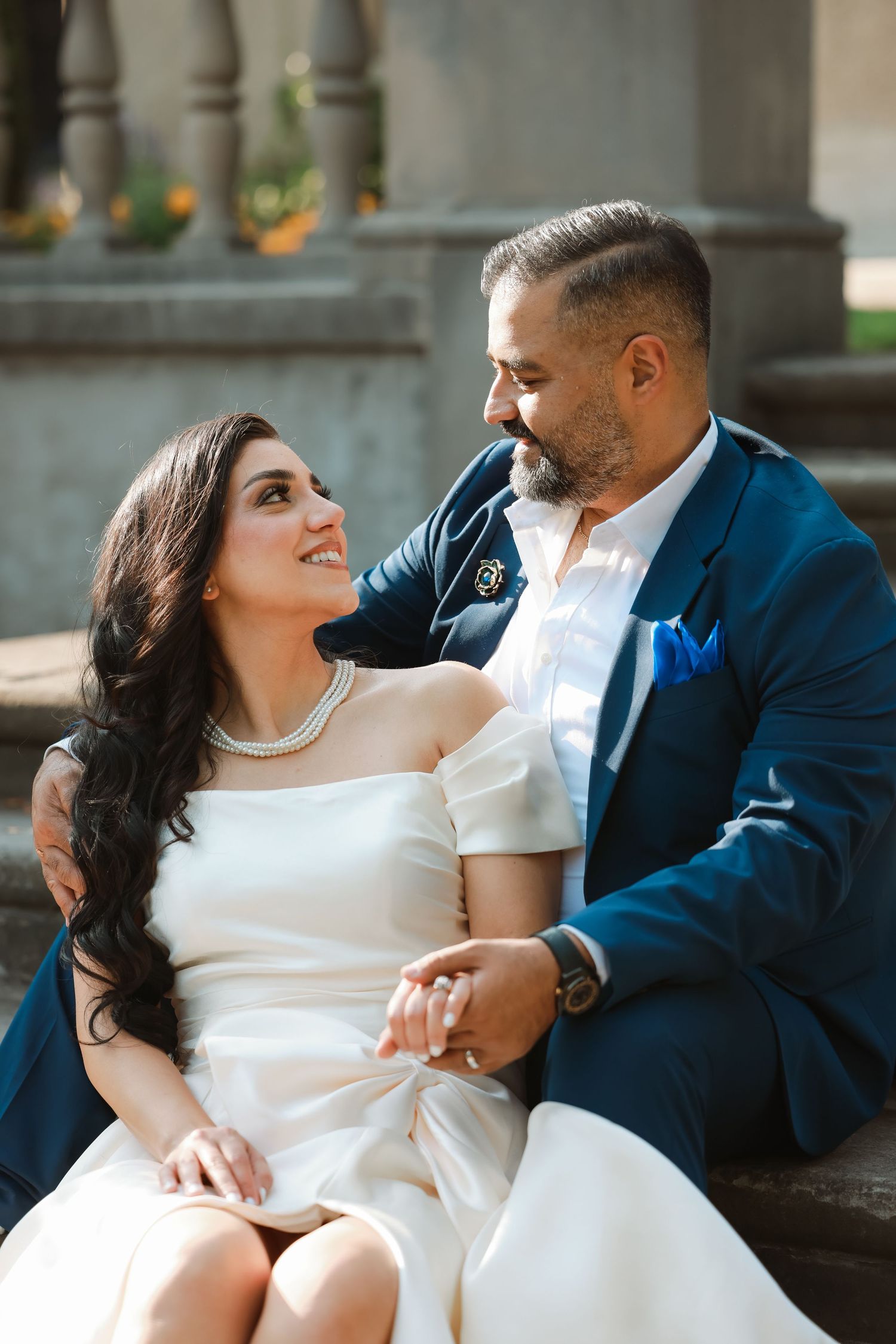 A couple shares an intimate moment on stone steps during their wedding photoshoot.