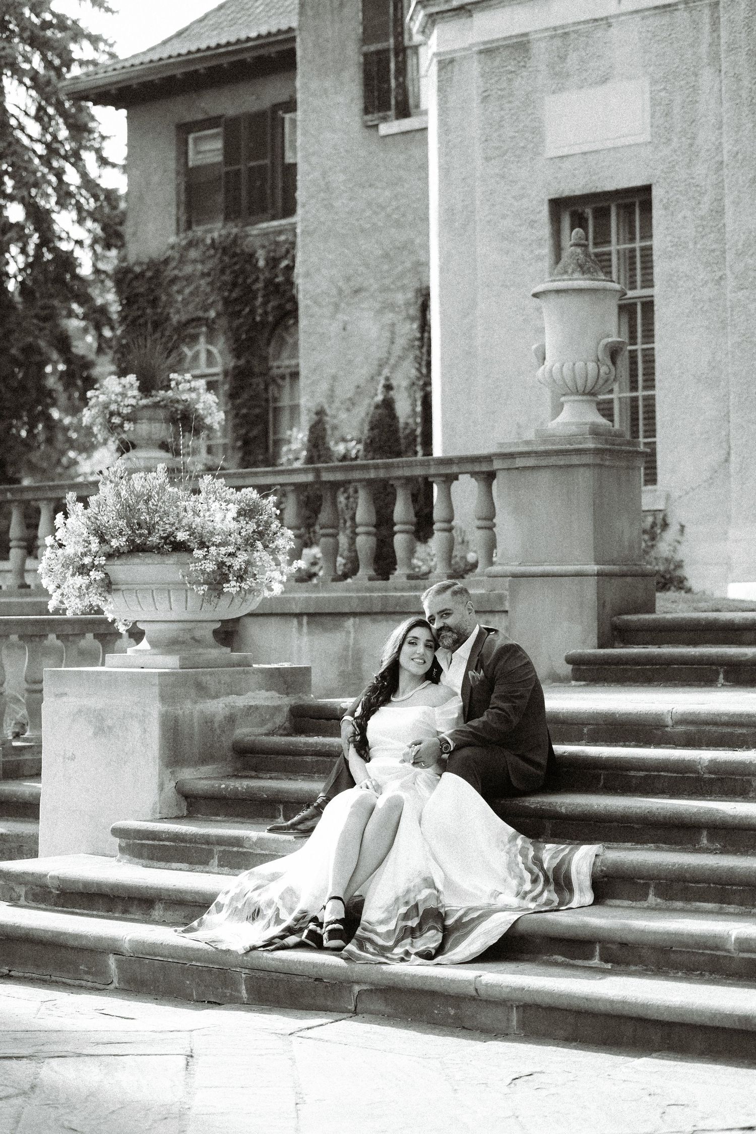 Black and white wedding photo on vintage mansion steps.