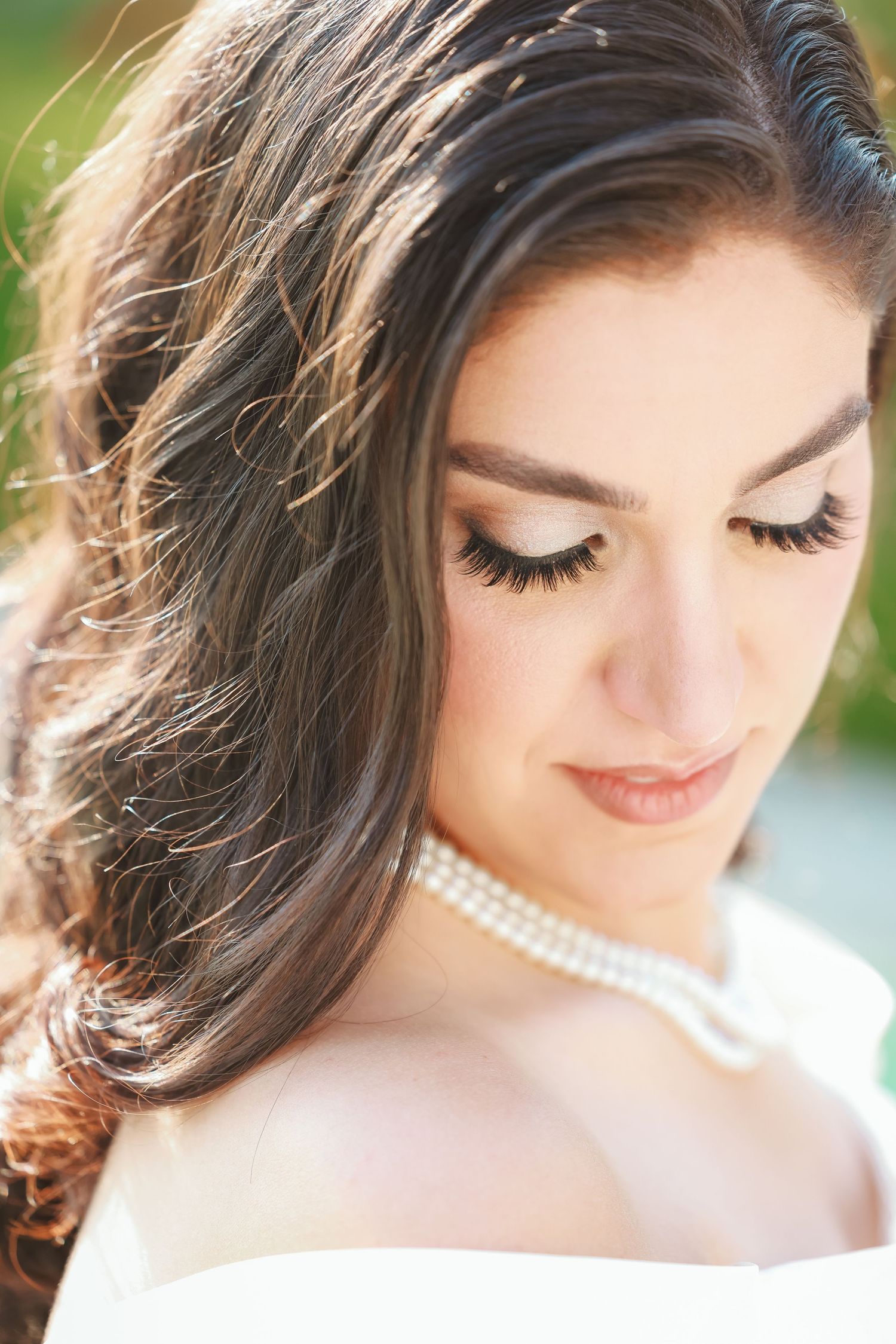 Close up portrait showing pearl necklace and delicate makeup with natural lighting.