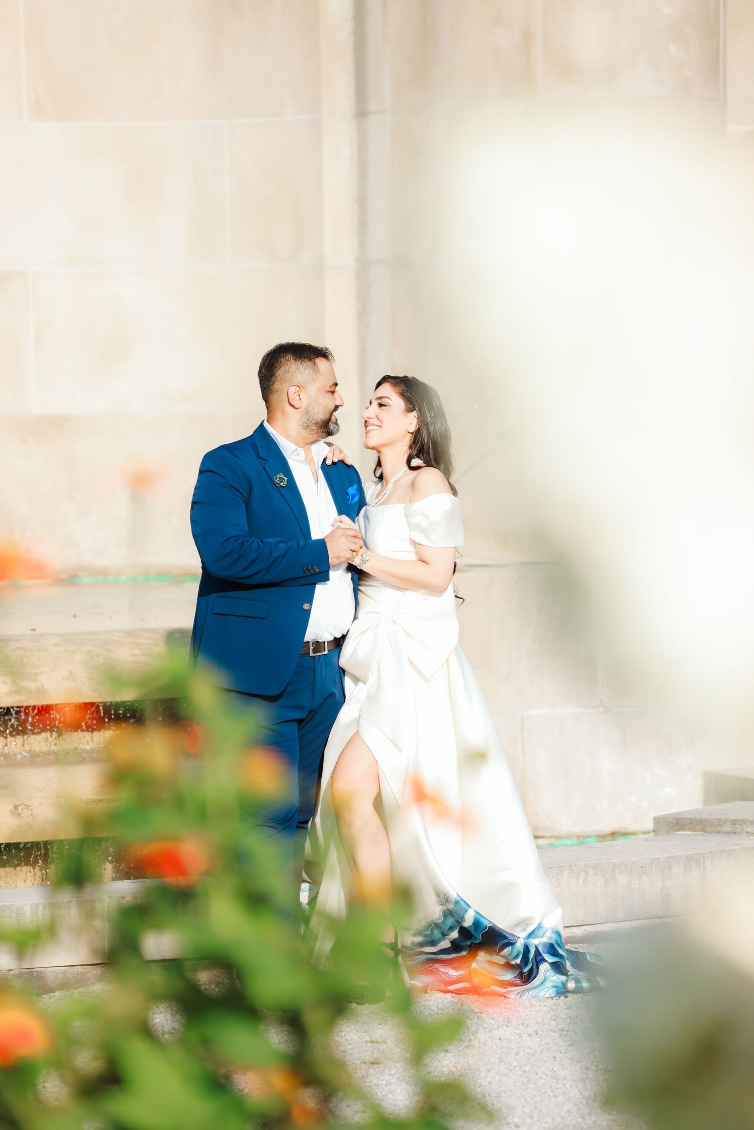 A romantic moment captured between a couple in formal wear against a light colored wall.