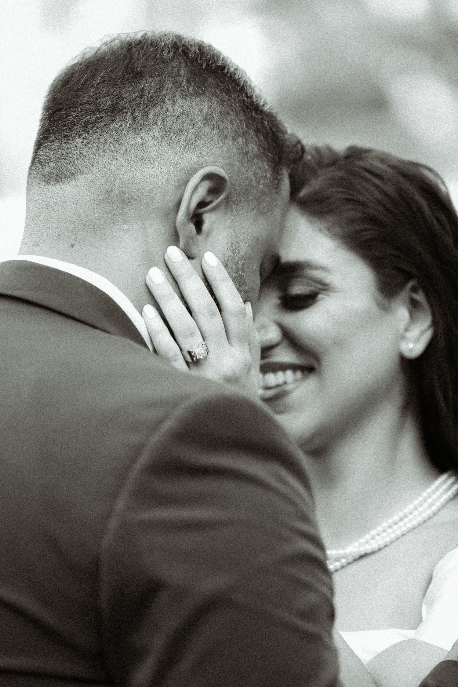 An intimate black and white portrait captures a tender moment between newlyweds.