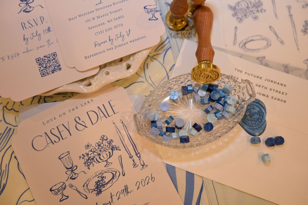 Blue and white wedding invitation suite for Casey and Dale with RSVP card, QR code, wax seal beads and a gold stamp on a table.
