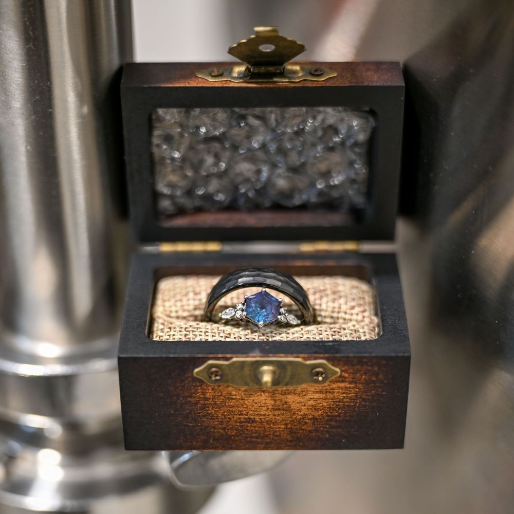 Black tungsten ring with blue sapphire in vintage wooden ring box.