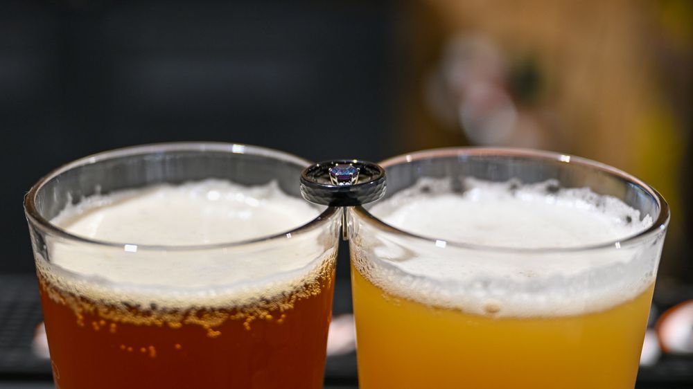 Two glasses of craft beer, one amber and one golden ale, clinking together in a celebratory toast.