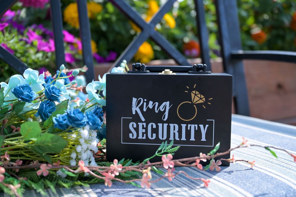 Black Ring Security box for weddings displayed on a table surrounded by colorful flowers.