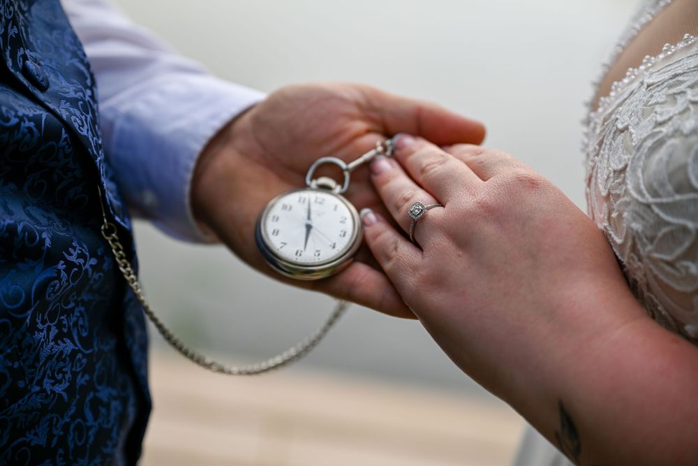 Bride and groom holding a vintage silver pocket watch during wedding ceremony.
