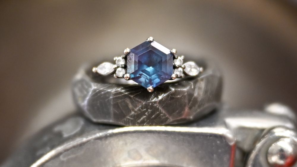 Elegant hexagonal blue sapphire engagement ring with diamond accents on a textured silver band.
