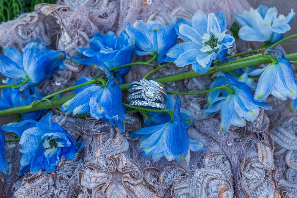 Blue bell flowers with a diamond ring resting on gray lace fabric.
