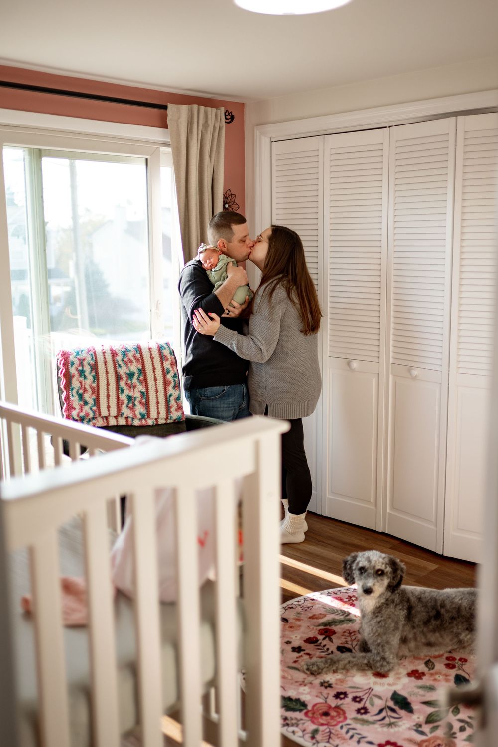 A cozy nursery room interior with white crib, closet doors, and floral rug.