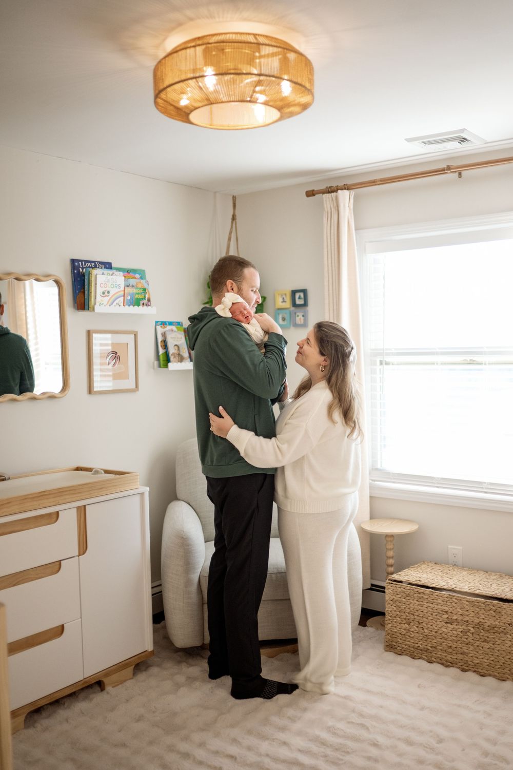 A couple in a bright room share a tender dance moment together while wearing white and dark clothing.