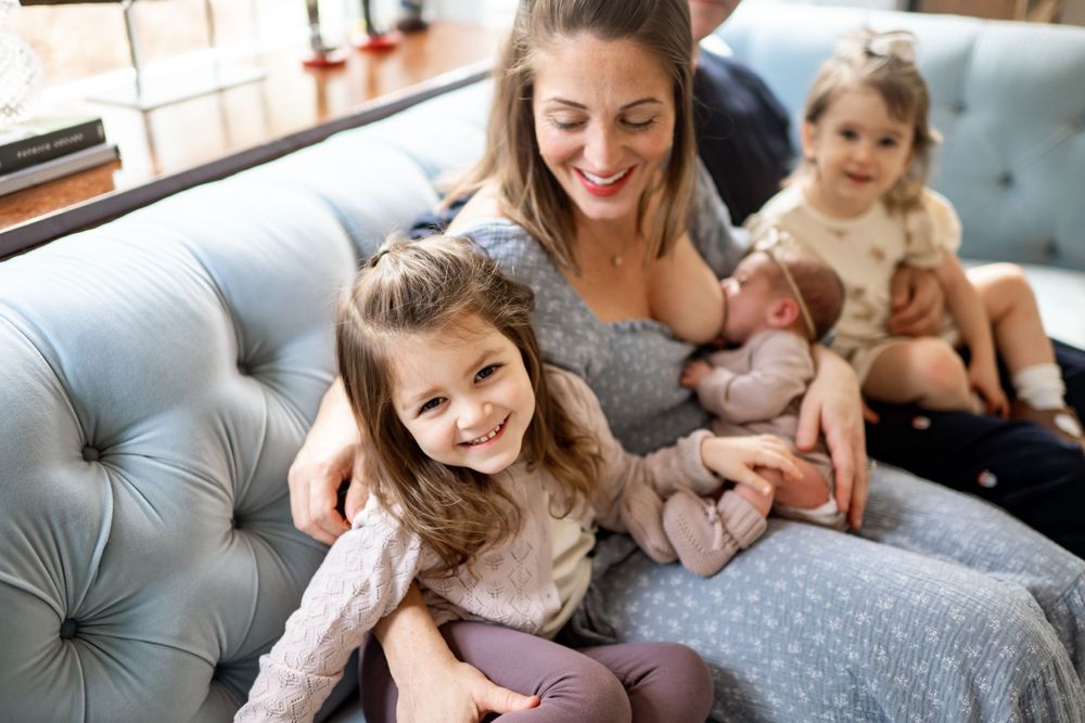 Joyful family gathering on blue tufted sofa with newborn and children.