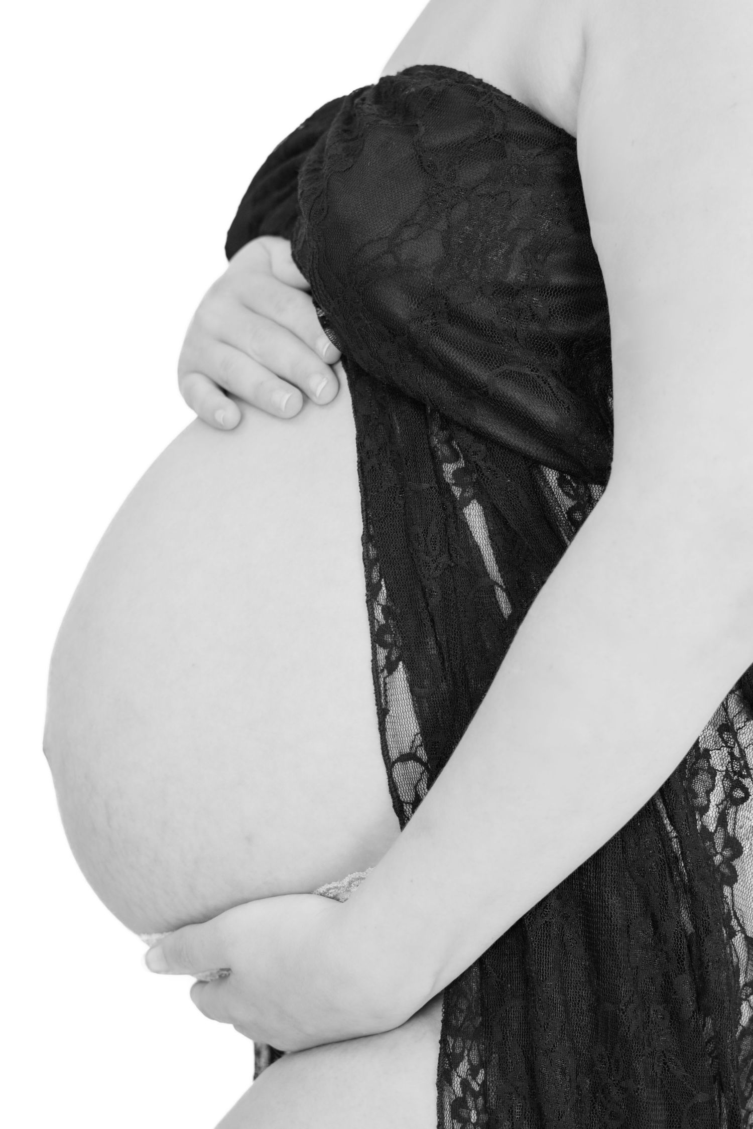 A series of black and white maternity photos showing a pregnant belly against a dark background.