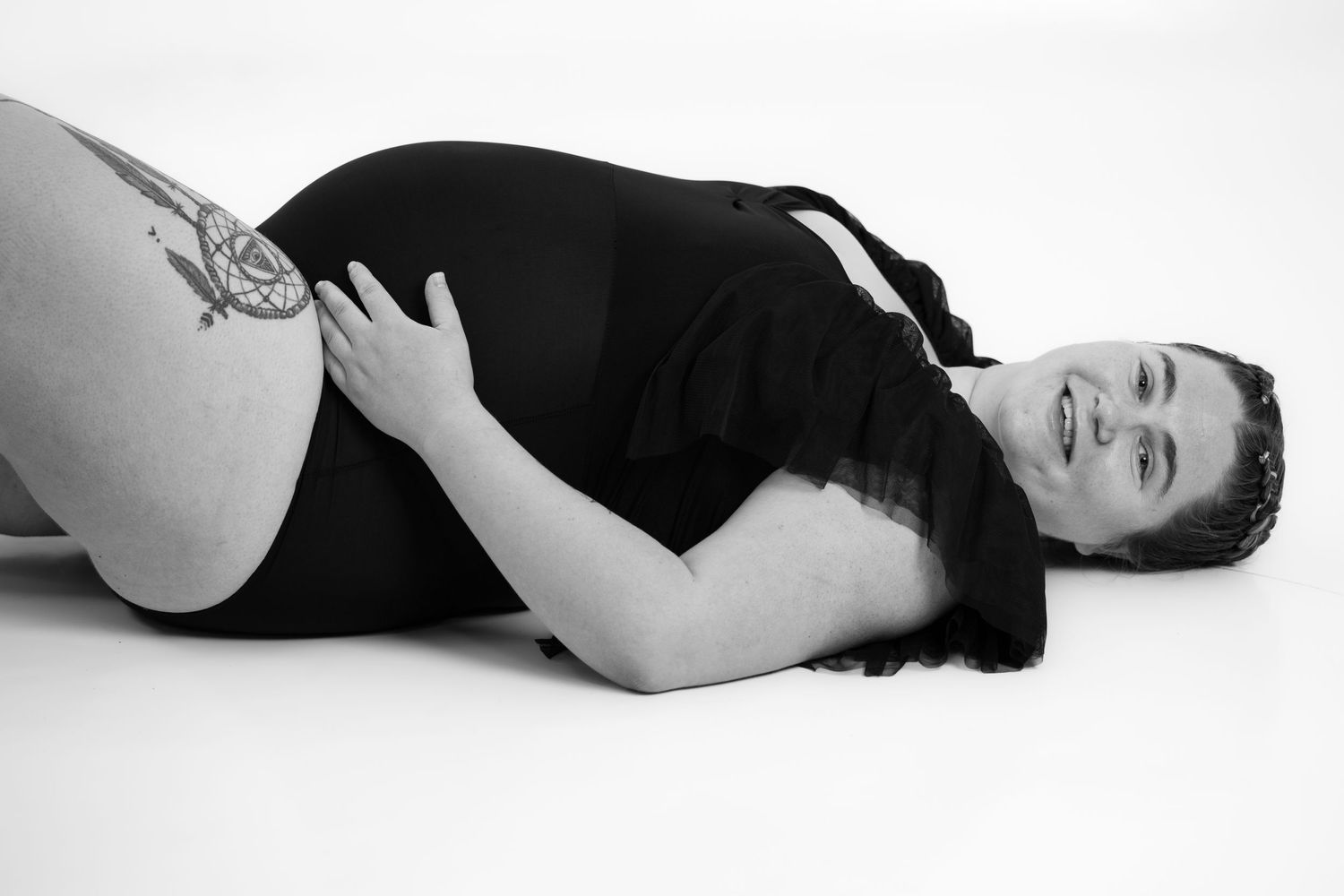 Black and white maternity photo with subject reclining in dark clothing.