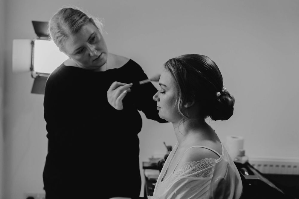 Black and white photo series of bridal makeup application in natural window light.