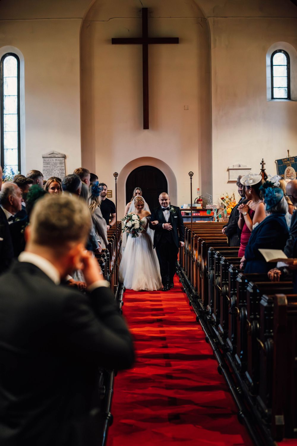 Wedding ceremony in traditional church with red carpet aisle.