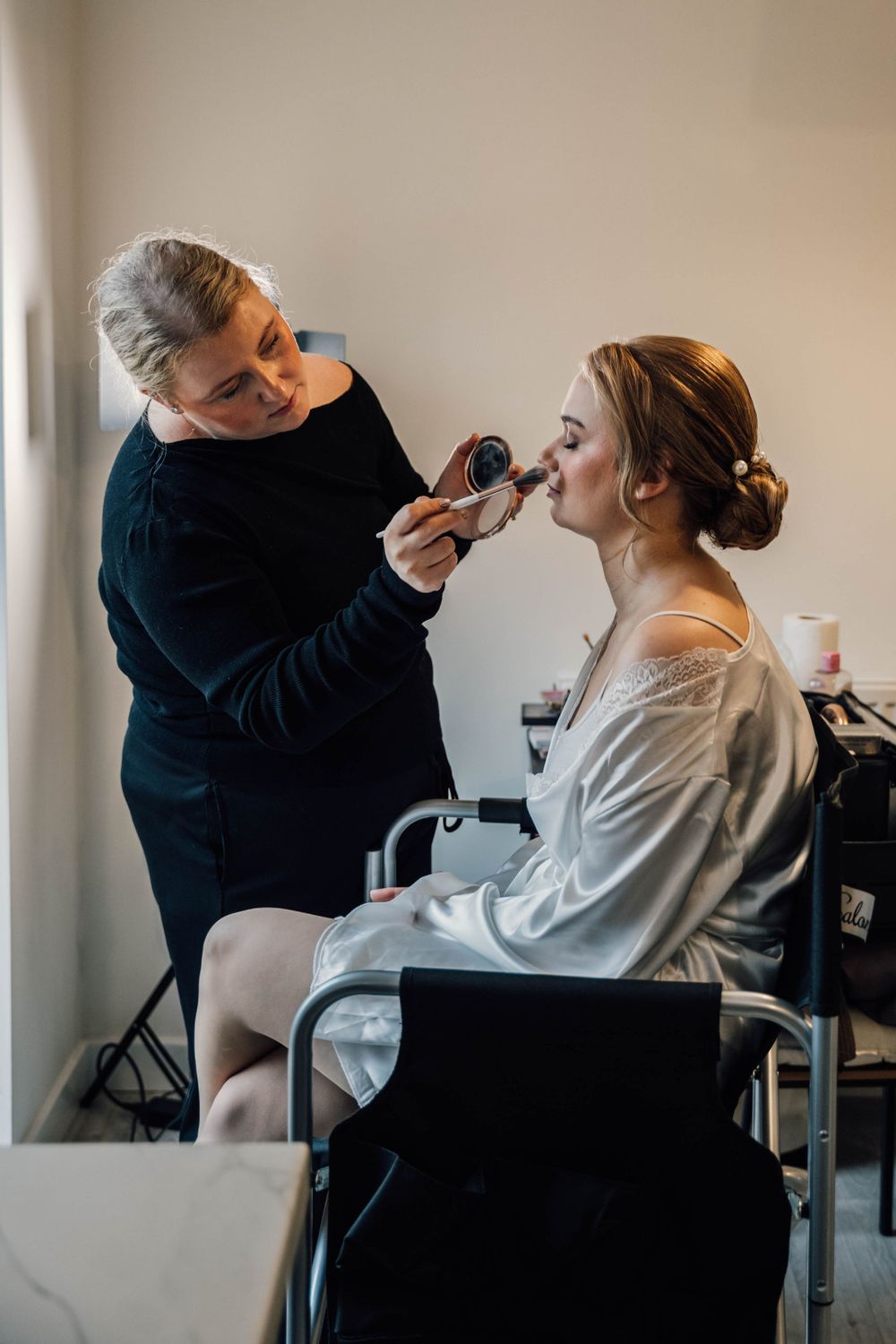 Professional makeup artist applying cosmetics to bride during wedding day preparations.