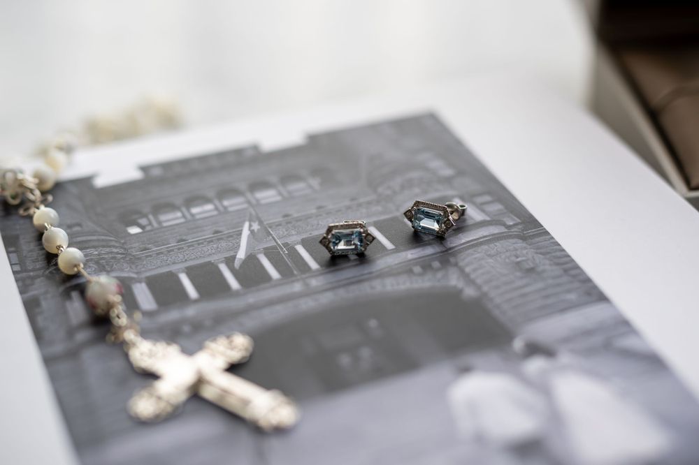 Rosary beads and wedding rings arranged on a black and white photo album.