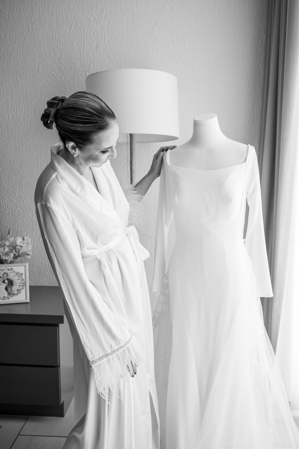 Black and white photo of wedding dress preparation with mannequin and robe.