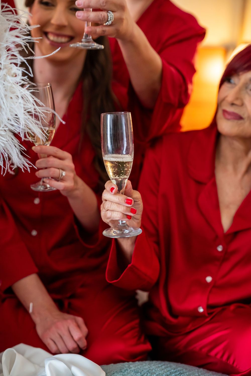Close-up of hands holding champagne glasses in festive celebration with red silk robes.